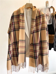 Dettaglio di sciarpa beige a quadri con frange indossata con blazer bianco e maglia