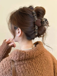 Detail view of leopard print plush claw clip with a brown heart accent in hair
