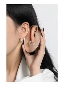 Detailed view of silver multi-layered geometric hoop earrings worn by a model