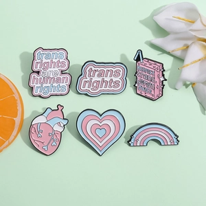 Transgender rights enamel pin set with rainbow heart and juice box designs on green background