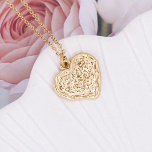 Detailed view of gold irregular heart pendant on a shell with pink roses background