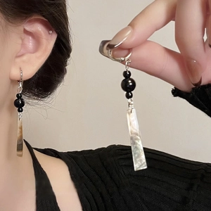 Detail of silver bamboo earrings with black beads and long geometric shell pendants