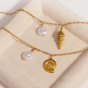 Detail of golden stainless steel necklaces with pearl and seashell pendants in a tray