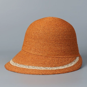 Detailed texture of handwoven orange straw sun hat with white crochet lace ribbon trim