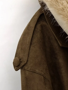 Détail de la texture en daim marron et du col en fourrure luxueux sur la veste