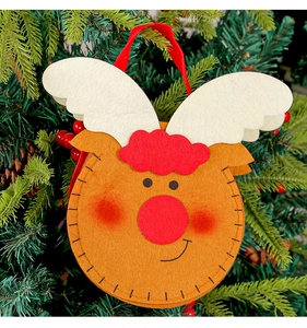 Close-up of reindeer felt ornament with red nose on a green Christmas tree branch