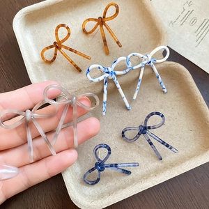 Gros plan de boucles d'oreilles nœuds en acétate avec motifs marbrés et écaille