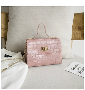 Détail d'un sac à main rose à motif crocodile avec fermoir doré et bandoulière chaîne