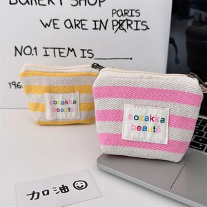 Detail of pink and yellow striped canvas makeup bags with colorful sozakka logo and metal zipper