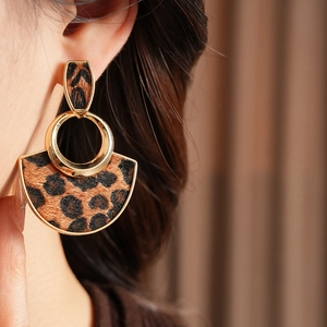 Close-up of leopard print fan-shaped earrings with gold frame on a model ear