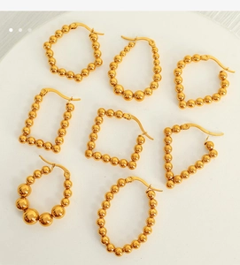 Detailed view of assorted gold geometric hoop earrings on a clean white ceramic tray