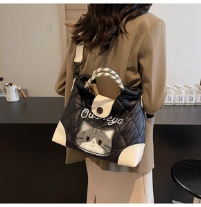 Detail of black quilted puffer tote featuring a cute cat embroidery and woven handle