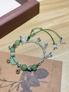Detail view of jade beads bracelet with silver butterfly and bamboo leaf charms