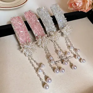 Floral crystal tassel hair clips with pearls in pink and silver set on beige fabric