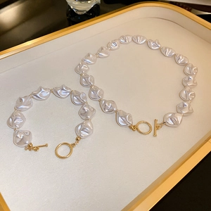 Vue détaillée de l'ensemble collier et bracelet en perles avec fermoir doré en T