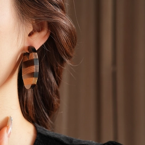 Close-up of geometric circular wooden earrings with natural textured brown stripes