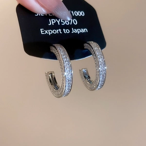 Detail of silver S1000 C-shaped earrings with white zircon stones on display card