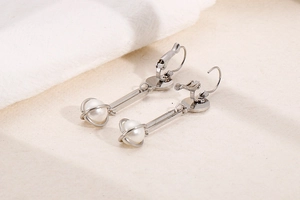 Detail of silver drop earrings with long metal bar and pearl in geometric wire cage