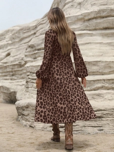 Back view of a long-sleeved leopard print dress with western cowboy boots on a desert rock