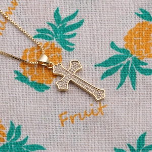 Macro detail of gold-plated cross pendant with sparkling zircons and box chain