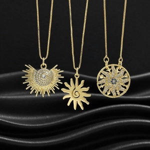Detailed macro view of three golden sun-shaped pendants with zircons on black silk