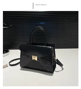 Detail of black crocodile texture patchwork on tote bag with gold rivet and double handles