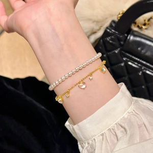 Detail of elegant gold chain heart bracelet and pearl bead strand worn on wrist