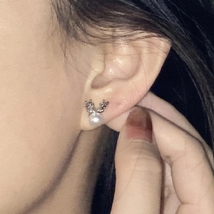 Close-up of elegant silver reindeer antler stud earring with a lustrous white pearl