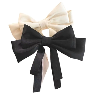 Elegant black and cream satin bow hair clips with long ribbons on a white background