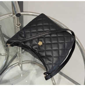Close-up of black quilted bucket bag featuring a golden camellia flower metal clasp