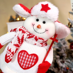 Christmas snowman plush doll with knitted scarf and red ski pole in warm festive lighting