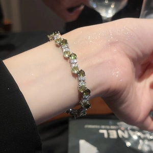 Macro detail of wave-shaped silver tennis bracelet with sparkling green zircons