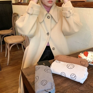Close-up of corduroy smiley face makeup bags in grey, beige, and brown on a wooden table