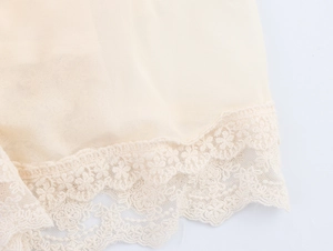 Gros plan sur l'ourlet en dentelle délicate et le tissu en mousseline beige d'une robe française