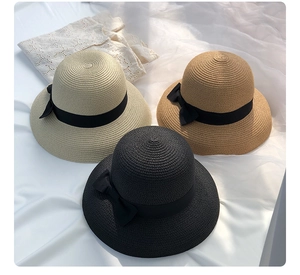 Top view of three woven straw sun hats in beige and black with elegant ribbon bows