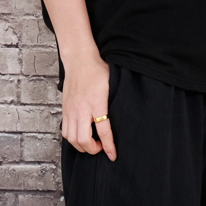 Close-up of golden minimalist pattern titanium steel ring worn on index finger