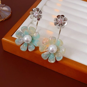 Detail of silver flower earrings with zircons, colorful petals and central pearl inlay