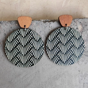 Macro shot of Bohemian wooden earrings with black and white floral patterns on stone surface