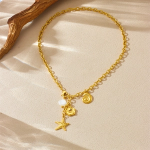 Vintage stainless steel necklace with gold starfish, seashell and conch charms on sand