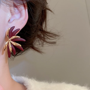 Close-up of 18k gold plated flower stud earrings with burgundy and gold petals