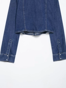 Détail de l'ourlet et des poignets d'une chemise en jean bleu foncé avec coutures doubles
