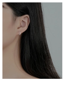 Close-up of minimalist 925 silver diamond-encrusted geometric hoop earrings on ear