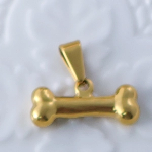 Macro shot of 24k gold plated bone-shaped pendant with polished metallic texture