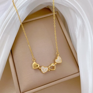 Detail of a gold heart pendant necklace with rhinestones on a beige leather display case