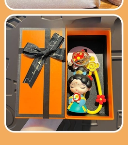 Close-up of cute Tang Dynasty style doll keychain in a premium orange gift box with ribbon