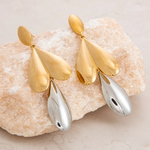Close-up of two-tone heart and teardrop earrings resting on a light natural stone