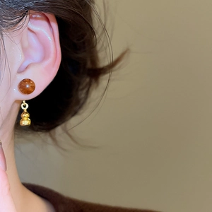 Détail de puce en résine marbre brun et pendentif gourde dorée porté à l'oreille