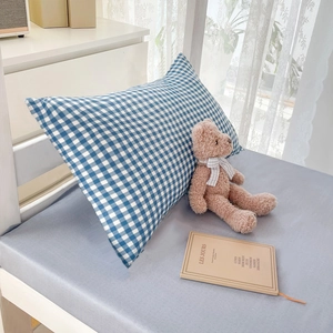 Minimalist blue and white plaid pillowcases on a gray bedsheet in a cozy bedroom setting