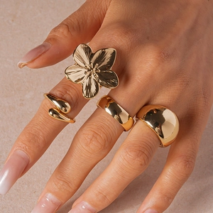 Detail of four-piece gold geometric rings set featuring floral and snake designs on finger