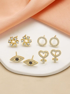 Macro shot of gold-plated earring set with zircon stones including evil eye and heart motifs